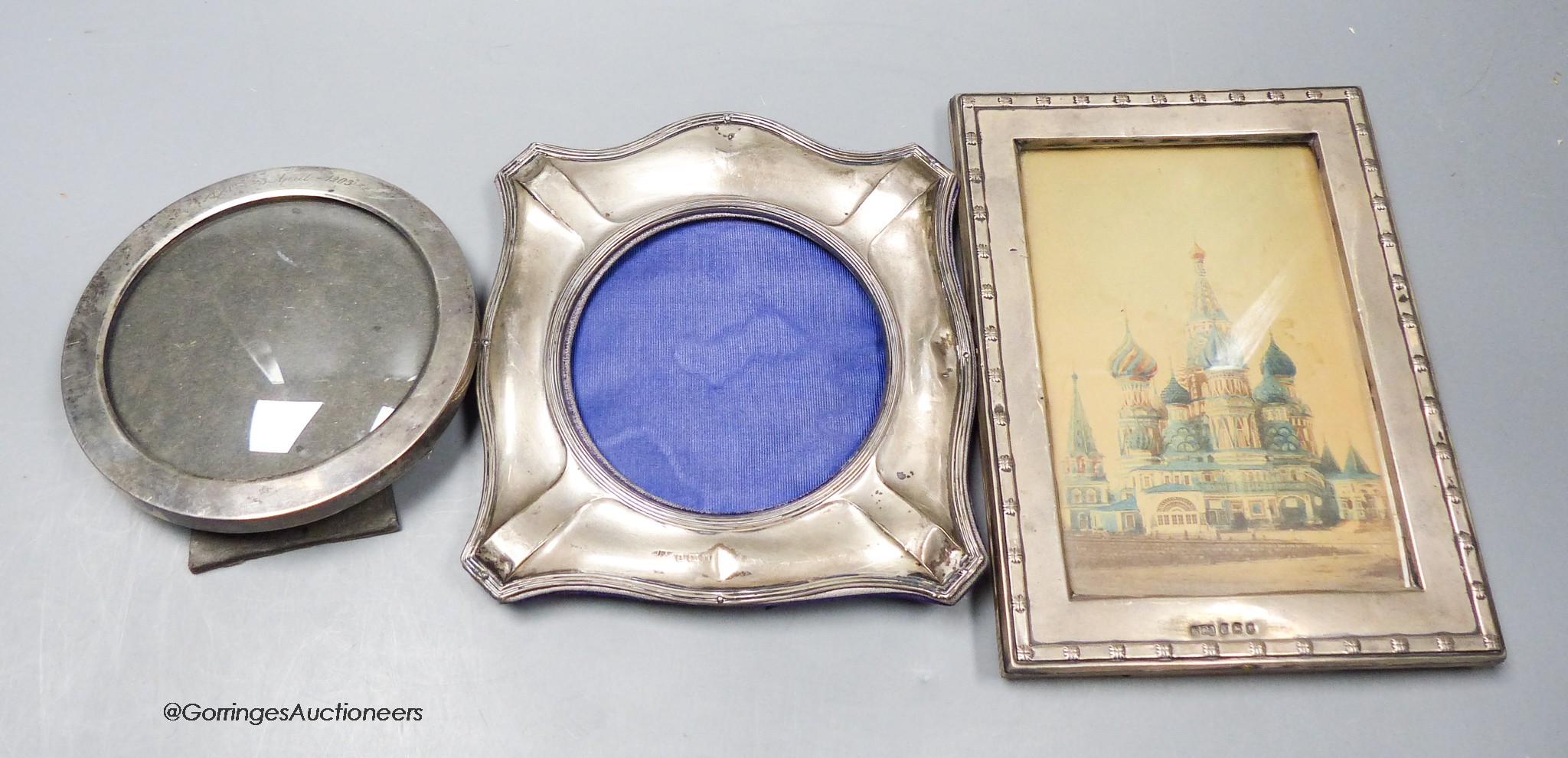 A late Victorian silver mounted circular photograph frame, 11.1cm and two later George V silver mounted photograph frames.